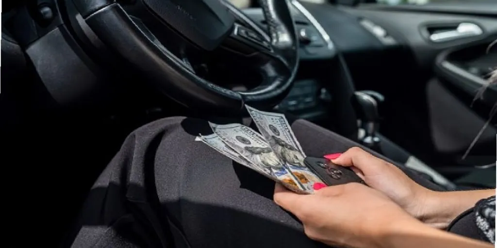 Professional chauffeur opening the door of a luxury sedan with a city skyline in the background