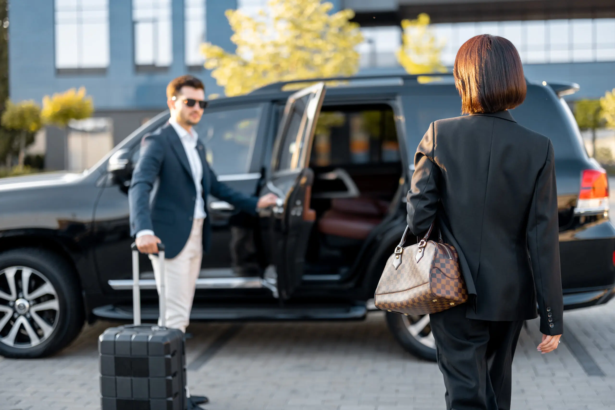 Professional chauffeur opening the door of a luxury executive vehicle for a business traveller