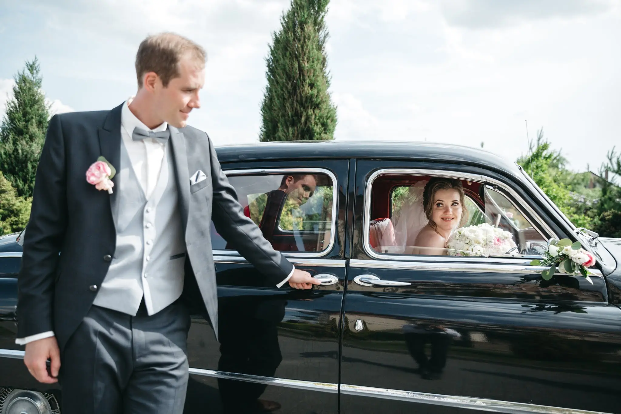 Elegant wedding couple stepping into a luxury chauffeur-driven car outside a wedding venue in Manchester