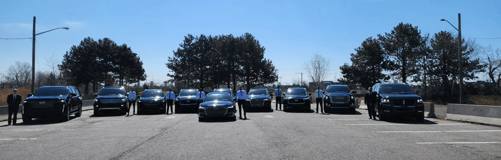 Line of luxury chauffeur vehicles including executive sedans and people carriers parked outside a modern building